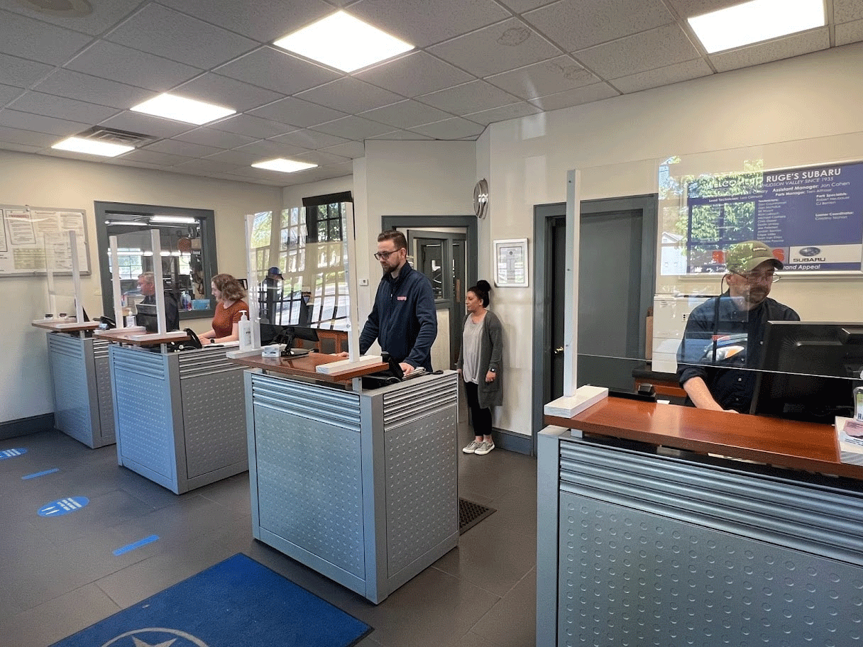 Customer representatives standing in their booths at a Subaru dealership in Rhinebeck