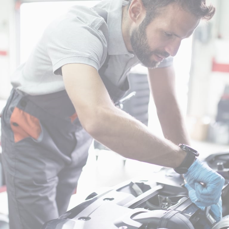 Mechanic standing over a vehicle's engine