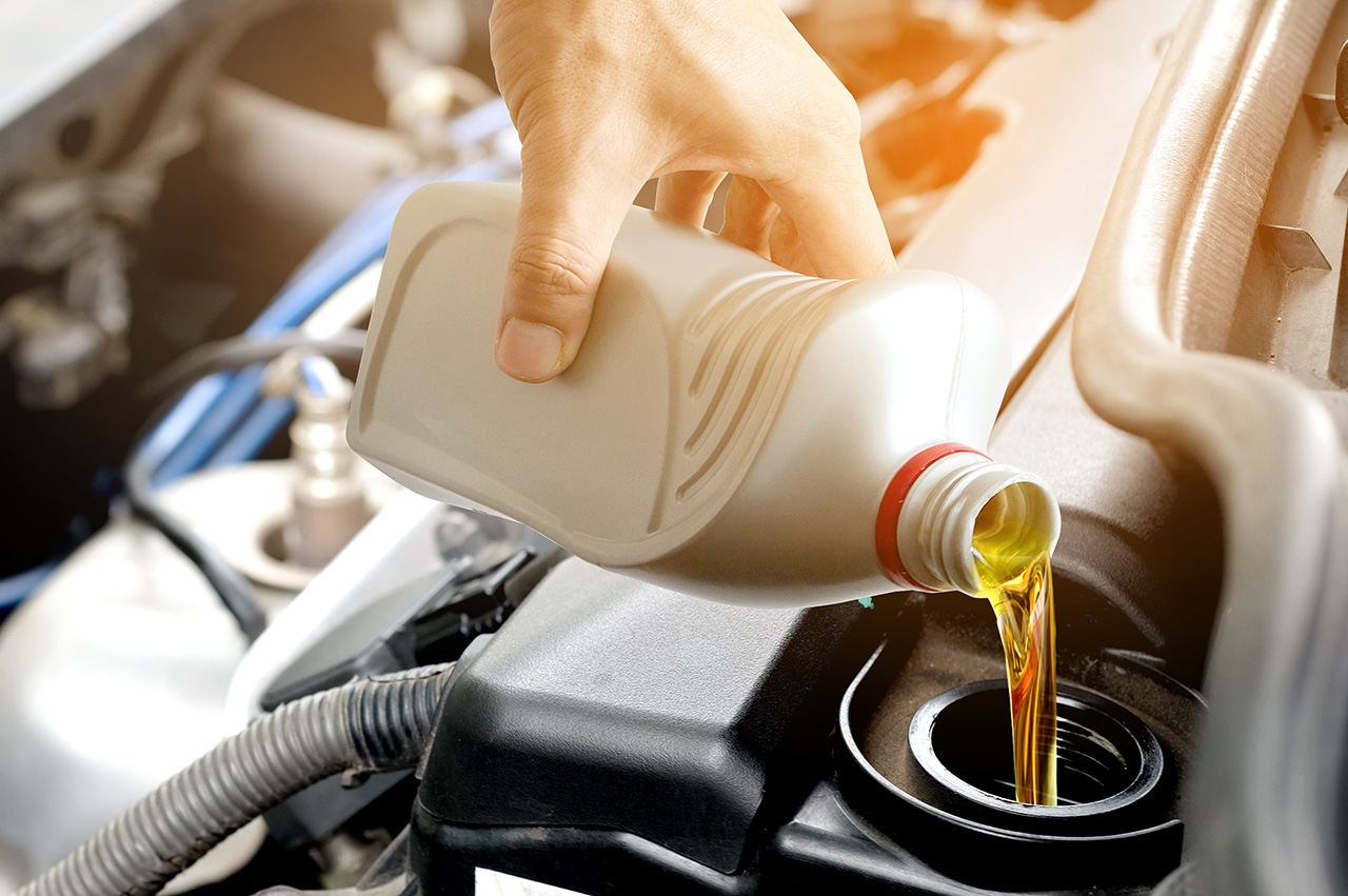 Mechanic pouring oil into car