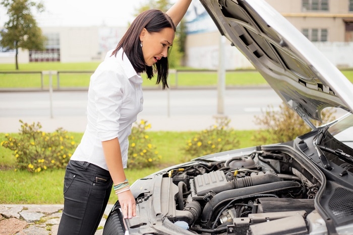 Woman looking under hood of car