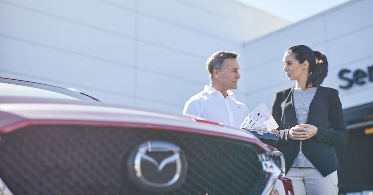 Technician and customer outside Mazda service center