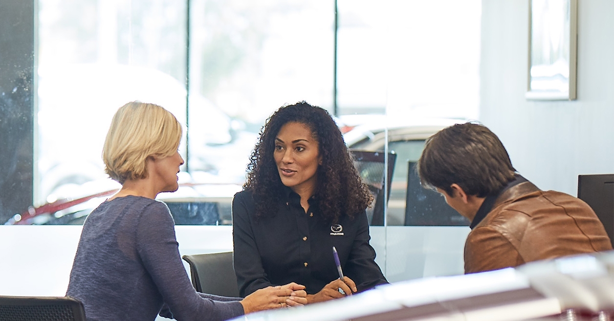 Mazda dealership talking with dealer at table