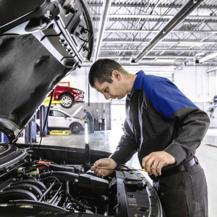 Ford service technicians checking oil fluid level on vehicle at service center