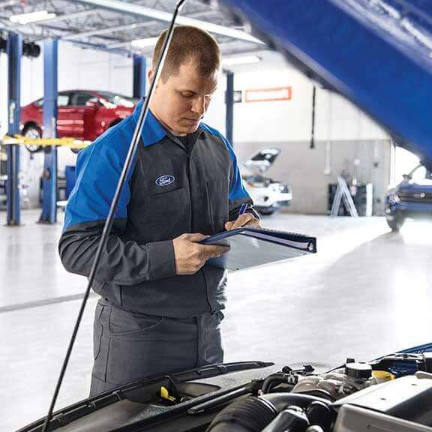 Ford service technician conducting service checklist on vehicle