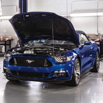 New blue Ford Mustang with open hood at service center