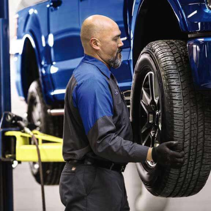 Ford service technician mounting car tire