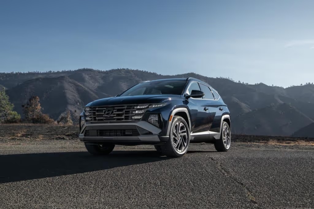 a blue 2025 tucson hybrid parked in front a sprawling mountainscape