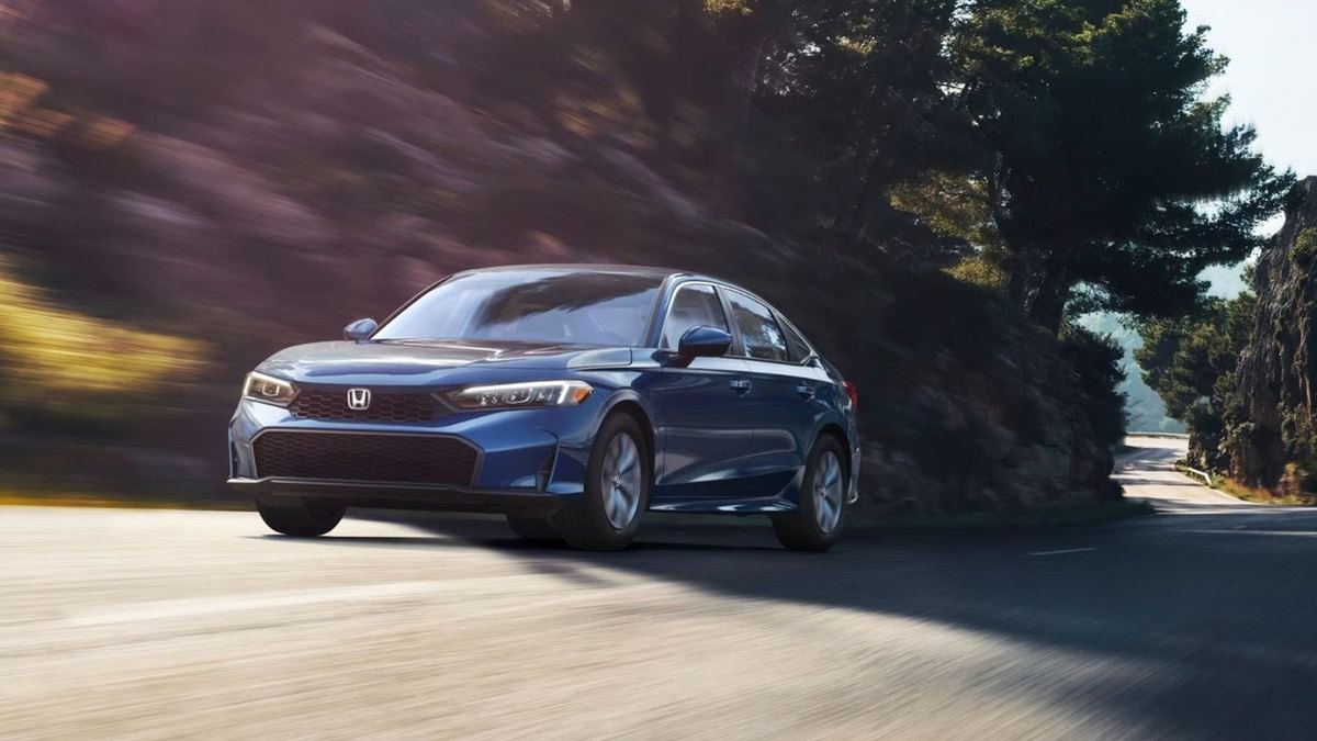 2026 Honda Civic sedan in blue driving on a winding tree-lined road