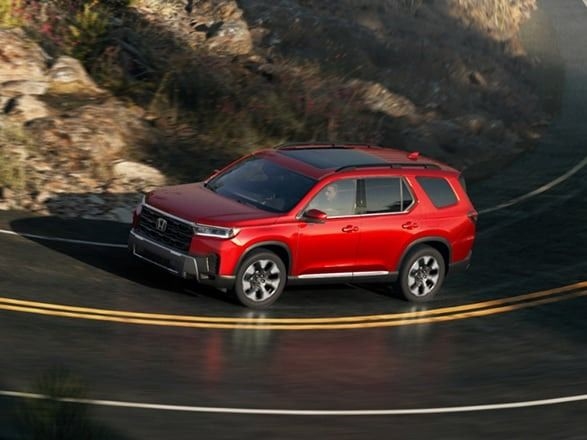 2026 Honda Pilot in Radiant Red Metallic driving on a mountain road