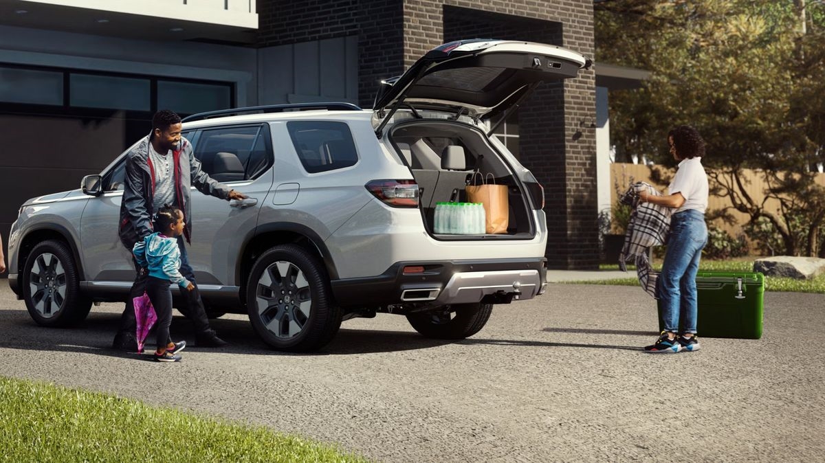 Family loading cargo into the back of a 2026 Honda Pilot with the power tailgate open
