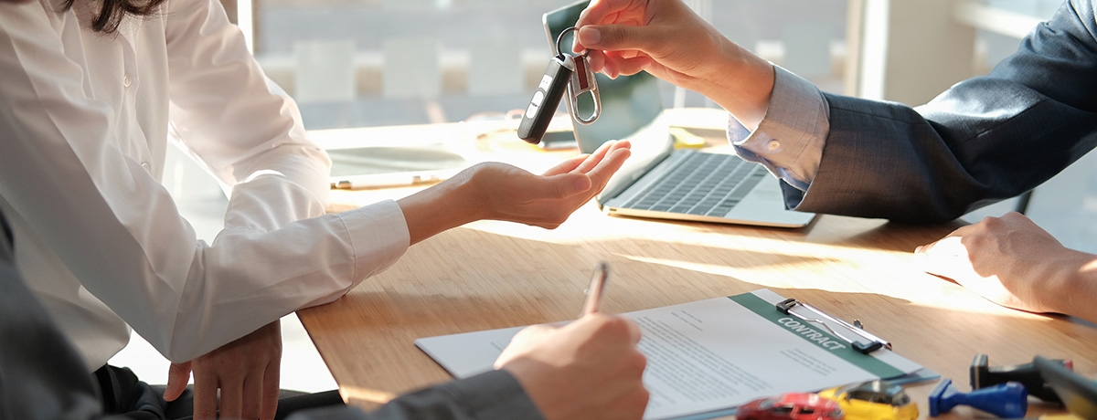 Customers signing documents at a car dealership