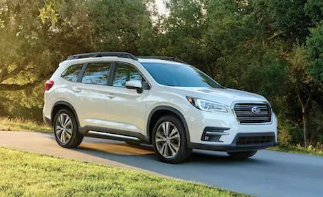 A white 2023 Subaru Crosstrek Hybrid is shown from the side on a city street.