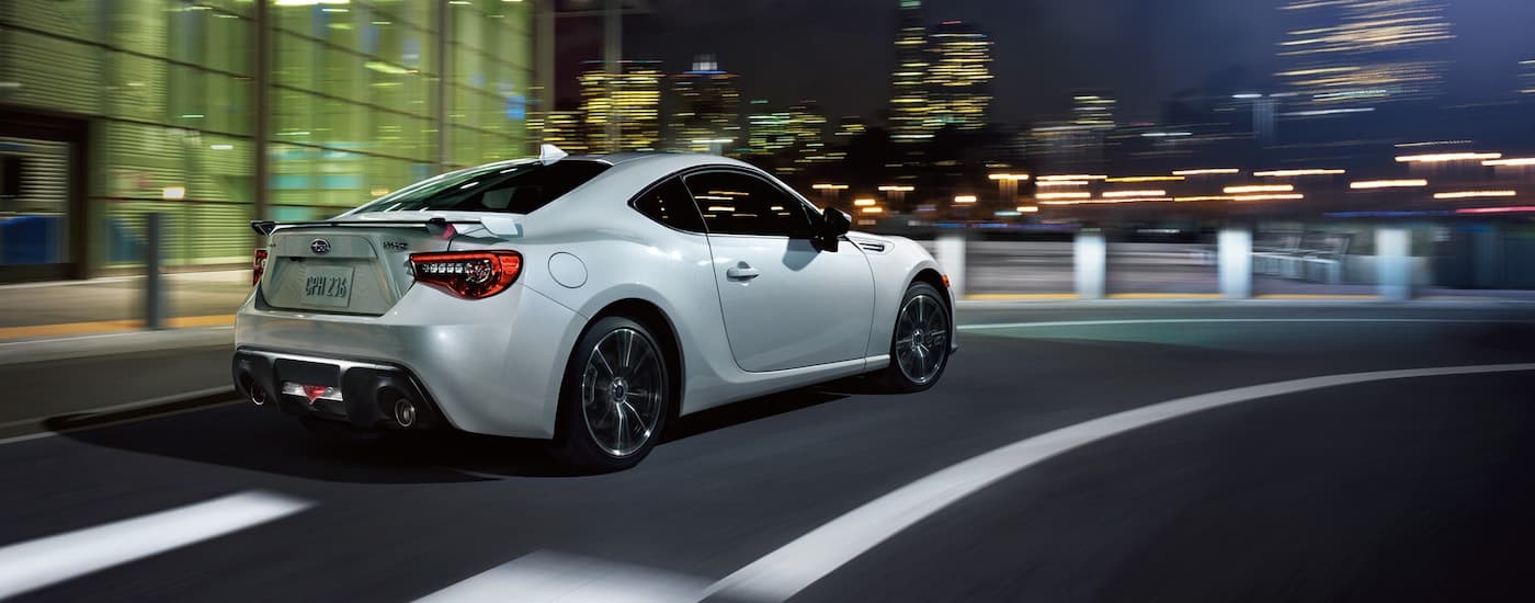 A white 2020 Subaru BRZ is shown driving through a city at night.
