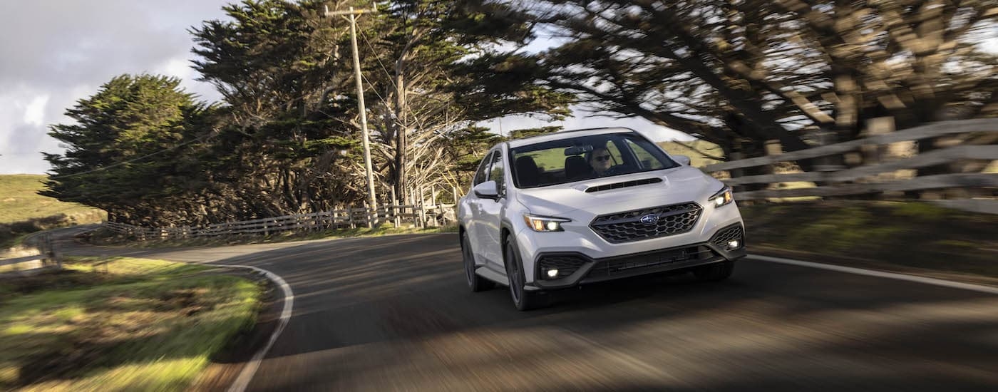 A white 2022 Subaru WRX is shown driving on an open road after leaving a Subaru dealer in Rhinebeck.