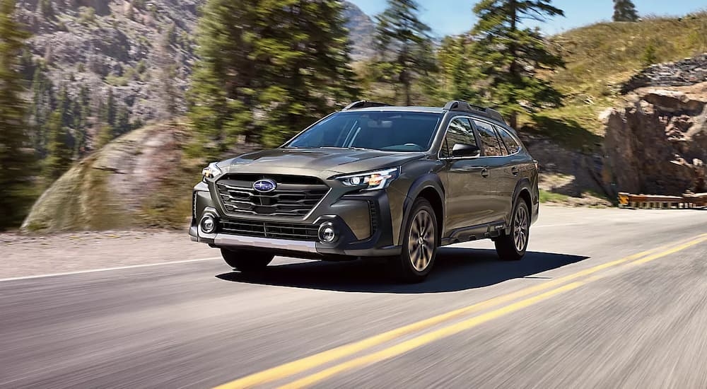 A grey 2023 Subaru Outback is shown driving on a highway.