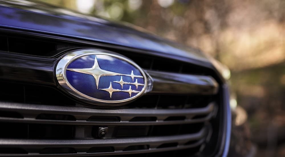 A close up shows the Subaru badge on the grille of a blue 2021 Subaru Outback.