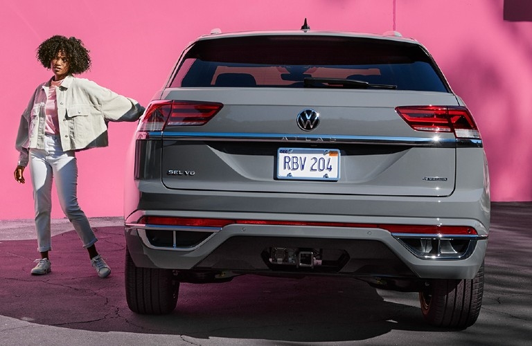 Rear view of 2023 VW Atlas Cross Sport with woman standing beside it