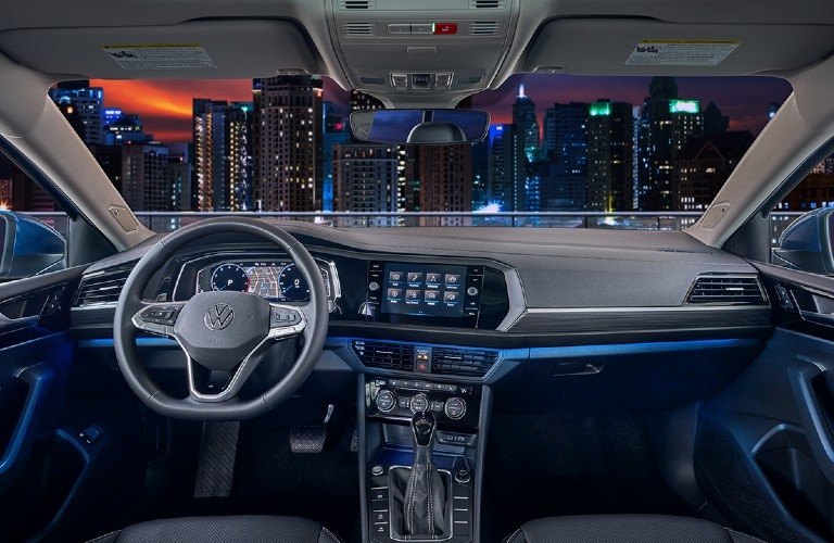 2023 VW Jetta interior steering wheel and dashboard with night time city skyline outside window