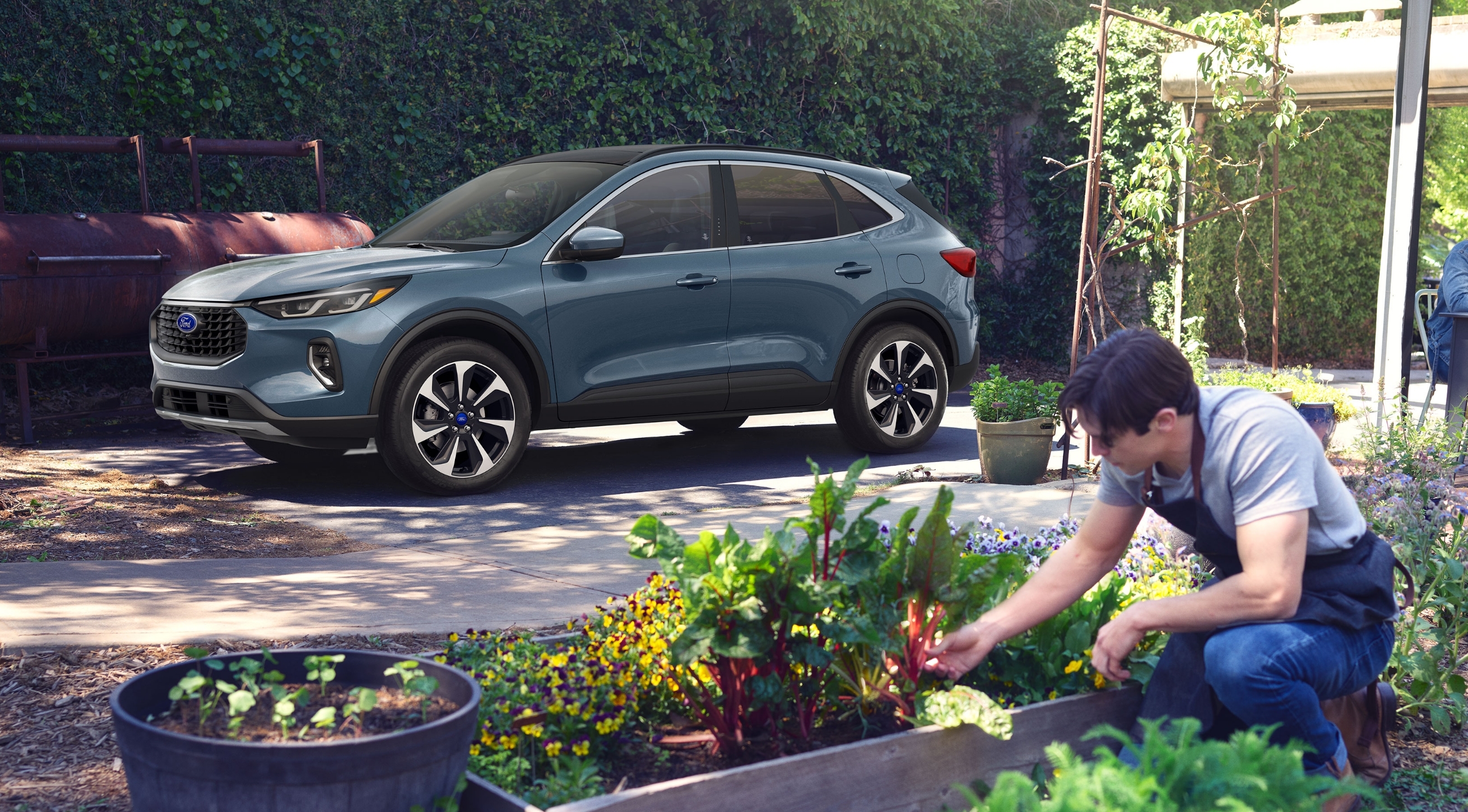 Young male kneeling down viewing garden with new 2023 Ford SUV parked in background