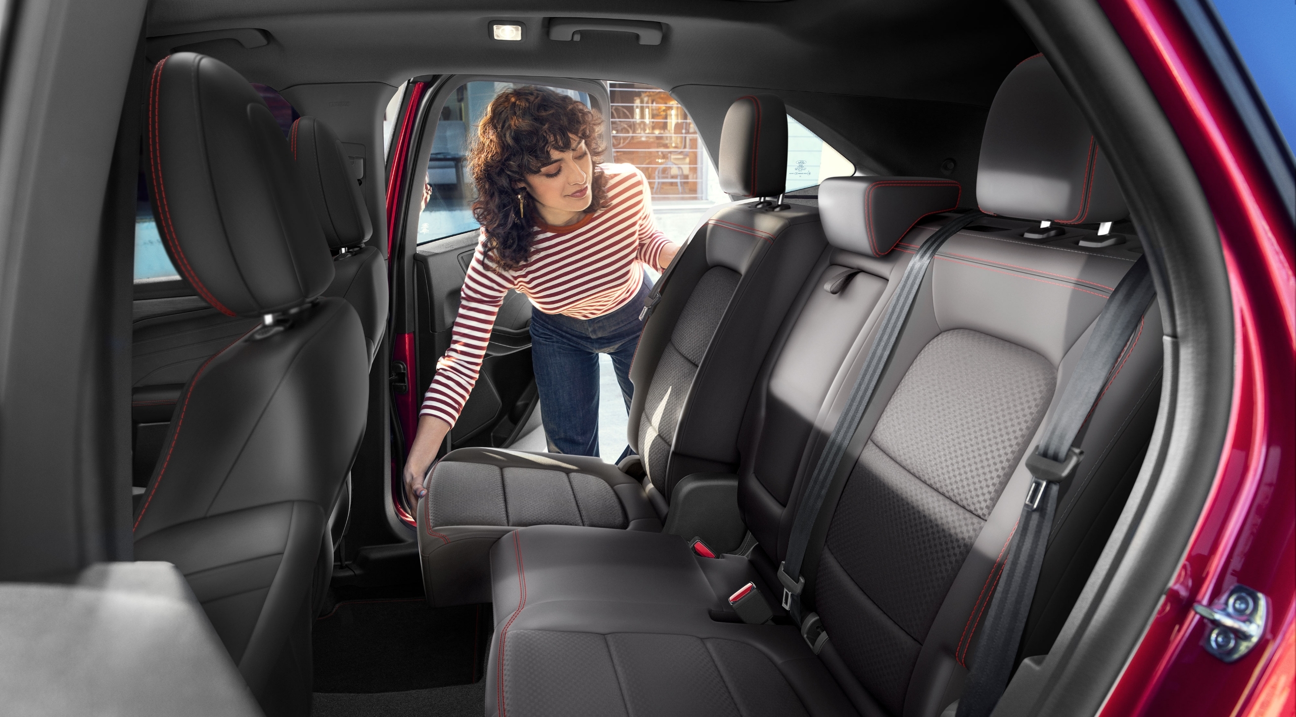Young female adjusting rear seats in a new red 2023 Ford SUV