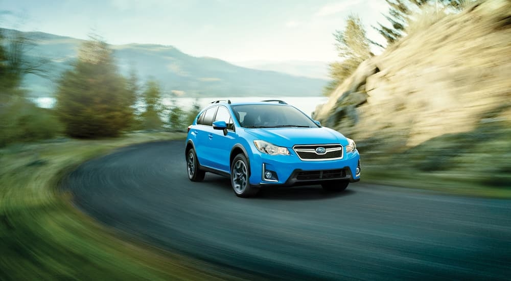 A blue 2016 Subaru Crosstrek is shown rounding a corner after visiting a used Subaru dealership.