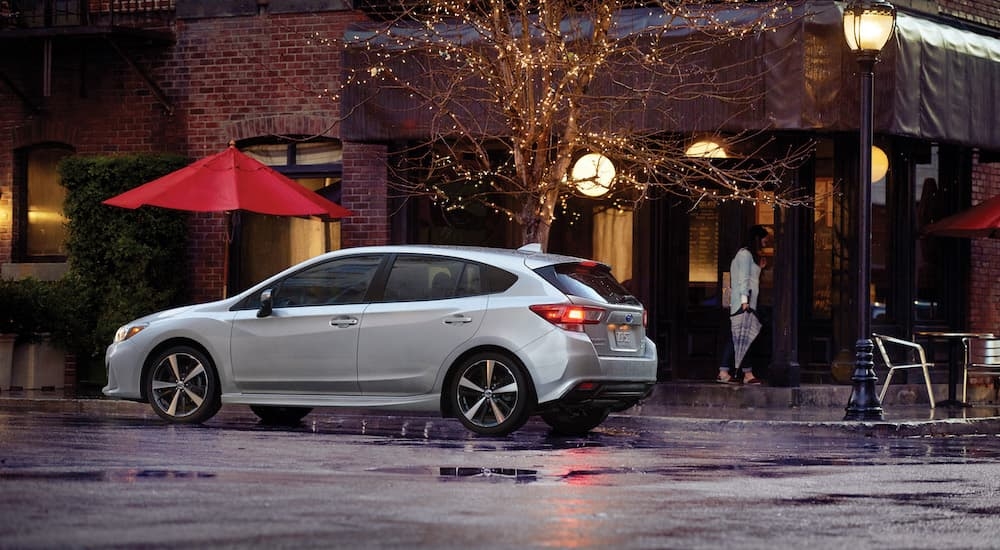 A silver 2019 Subaru Impreza Sport is shown on a wet city street.