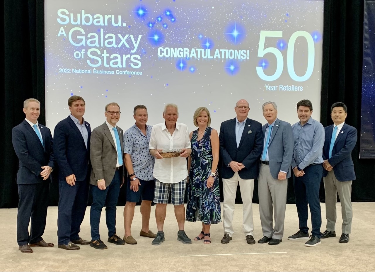 A group of people posing on a stage for Ruge's Subaru's 50th Anniversary.