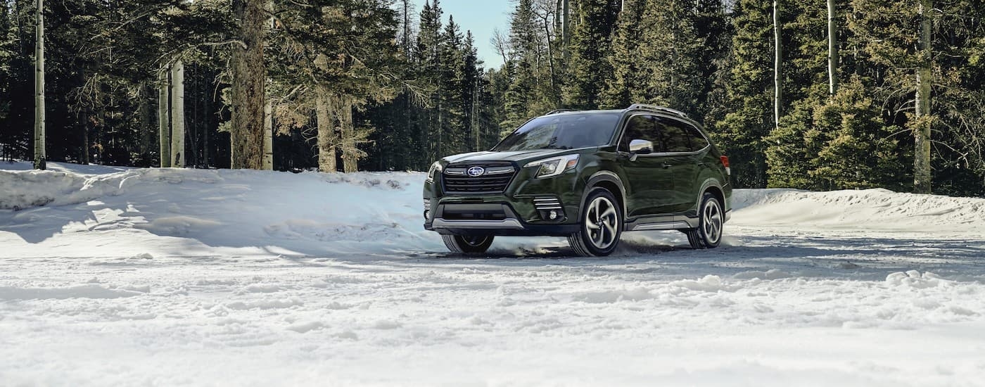 A green 2023 Subaru Forester is shown parked on a snowy field.