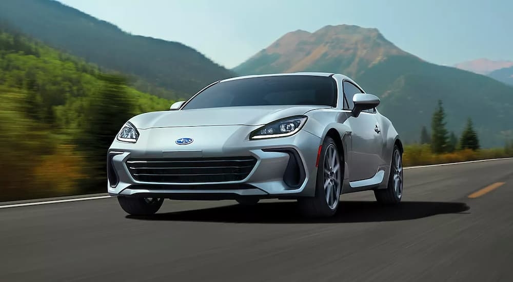 A silver 2023 Subaru BRZ driving past mountains after leaving a Subaru dealer.