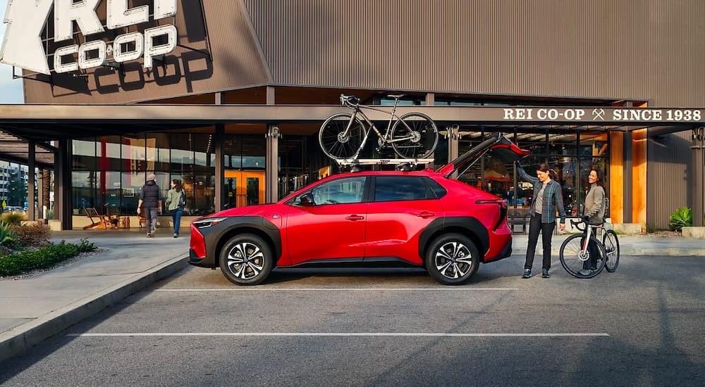 A red 2023 Subaru Solterra is shown from the side being loaded with bikes.