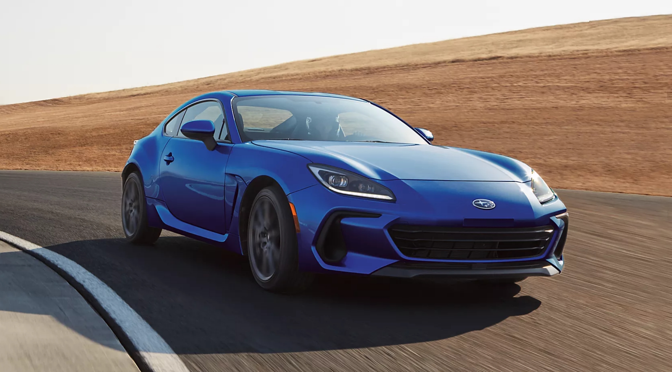 A blue Subaru sedan driving down a winding road.