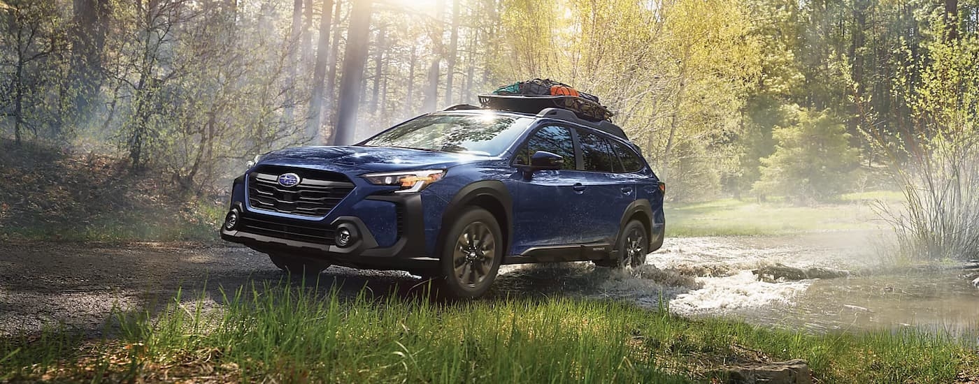 A blue 2023 Subaru Outback Onyx Edition is shown driving on a muddy trail.