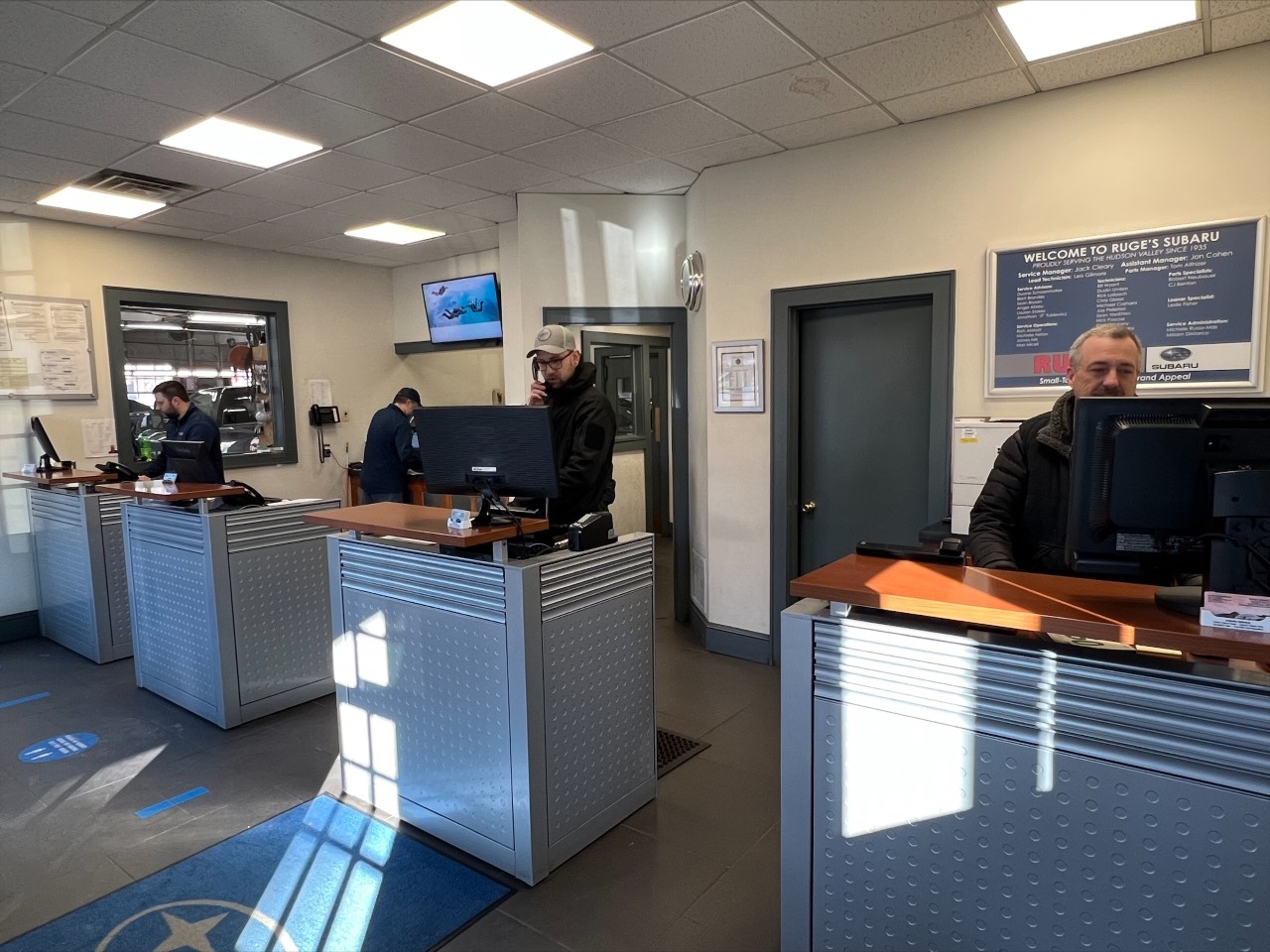 Customer representatives standing in their booths at a Subaru dealership in Rhinebeck