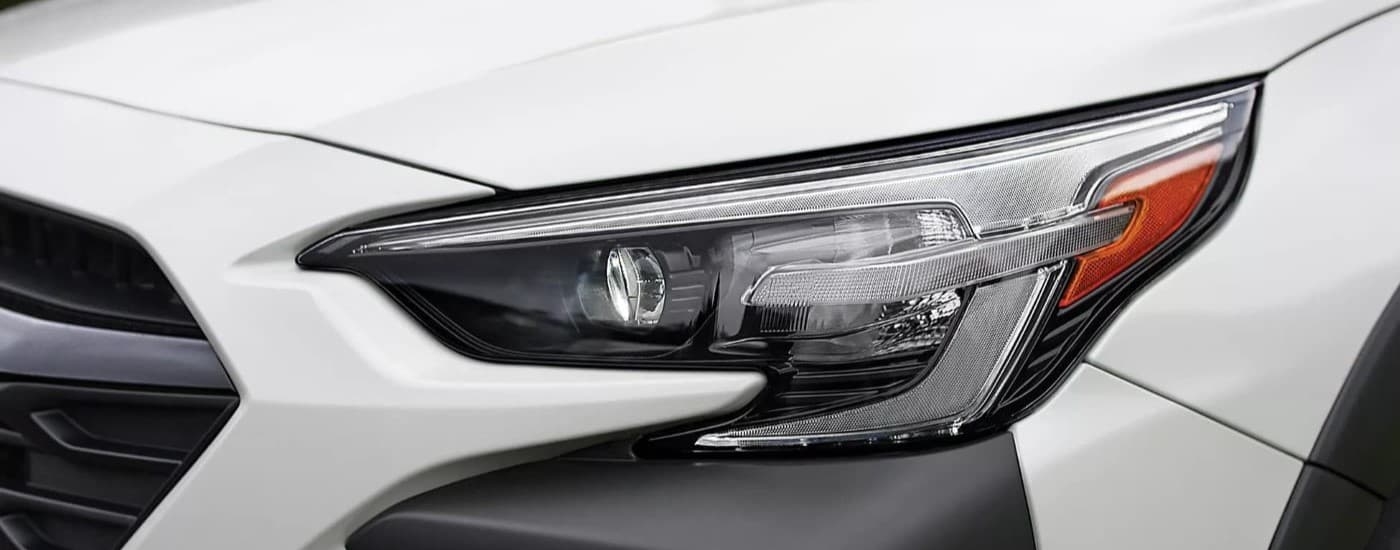 A close up shows the driver side headlight on a white 2023 Subaru Outback Onyx Edition.