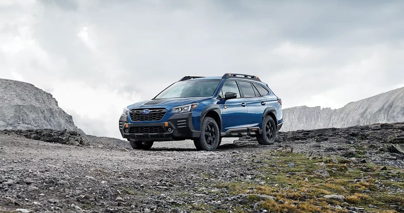 A blue  2023 Subaru Outback Wilderness is shown parked on a mountain path.