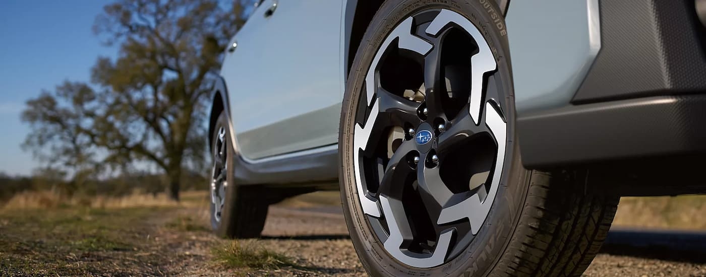 A close up of the side and tire of a 2023 Subaru Crosstrek is shown on a dirt road.