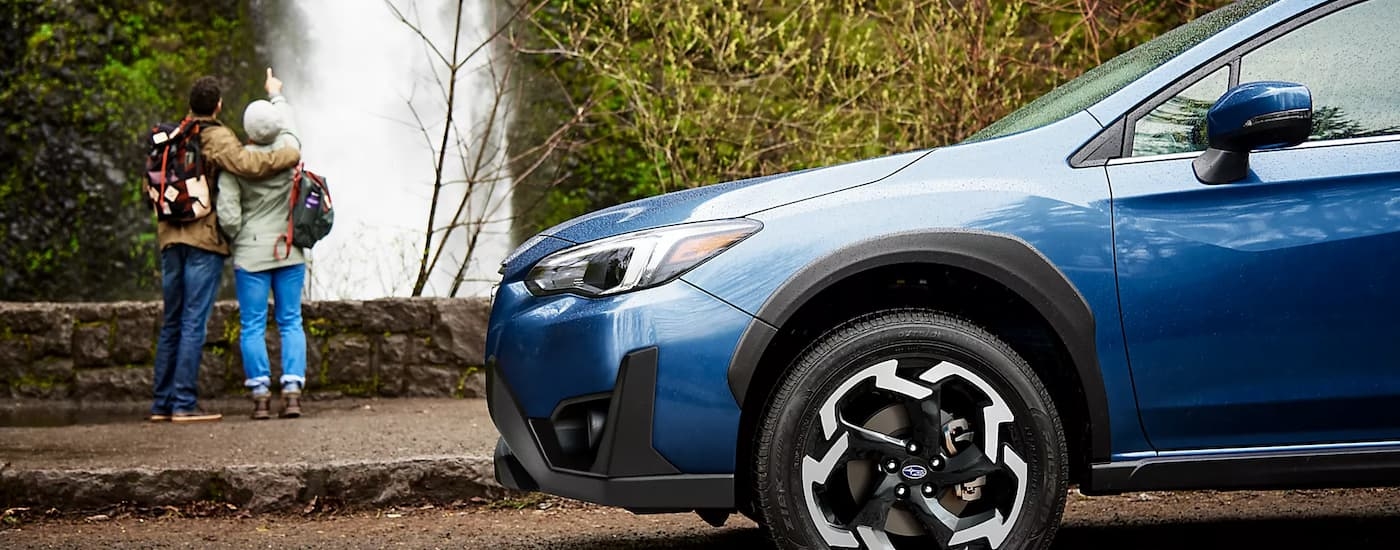 A blue 2023 Subaru Crosstrek Limited is shown from the side parked near a waterfall.