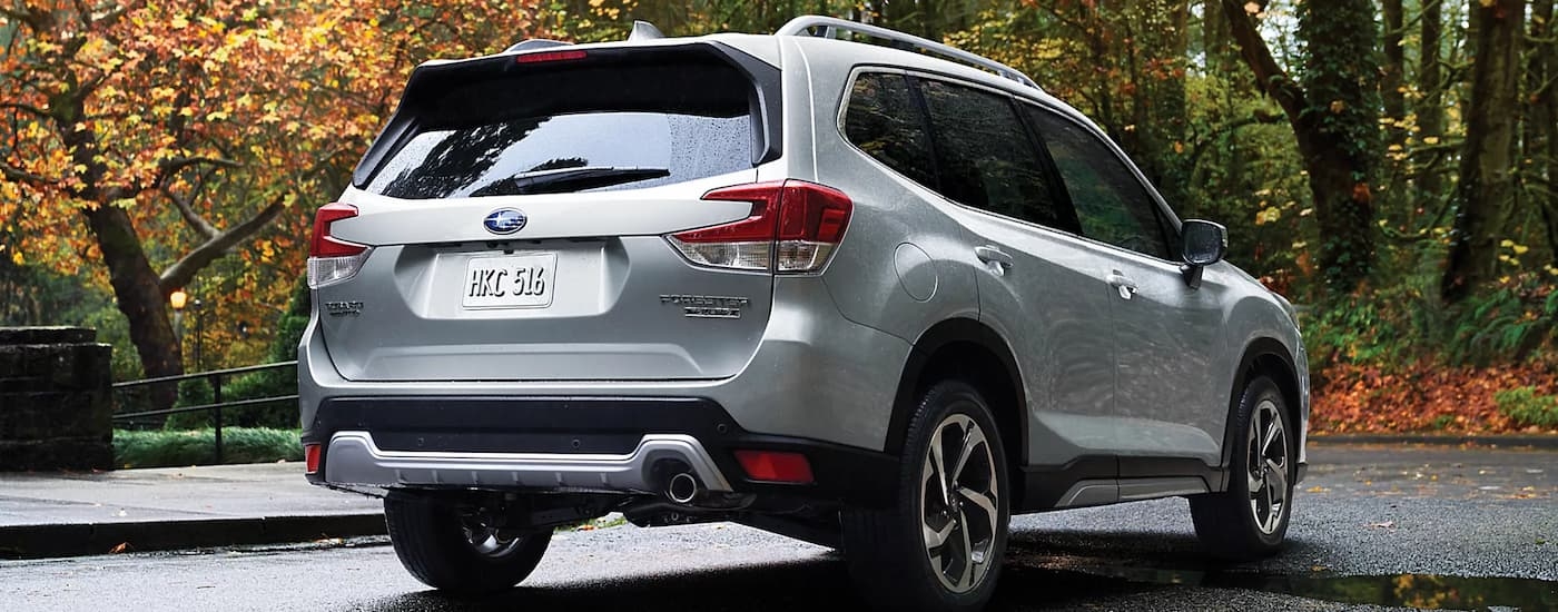 A silver 2023 Subaru Forester Touring is shown from a rear angle parked in an open lot.