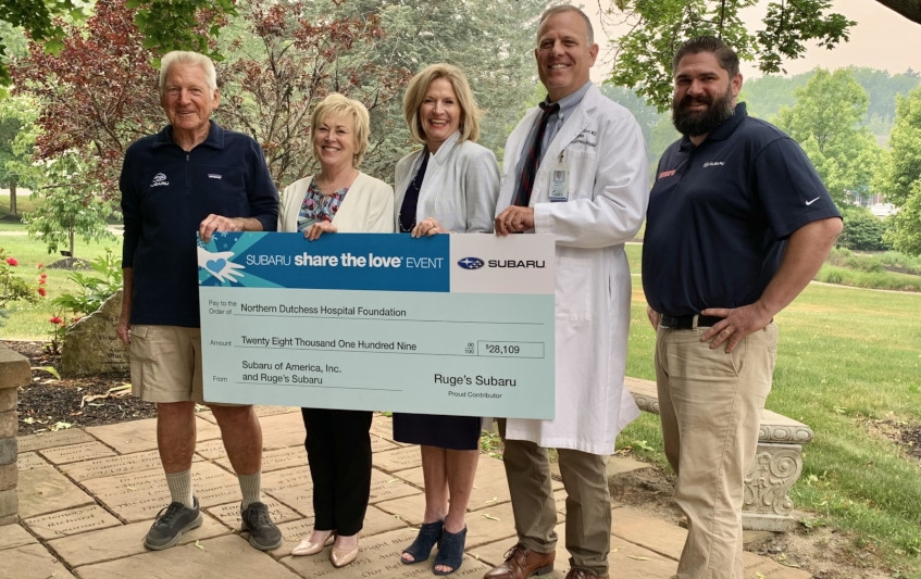 A group of Ruge's Subaru and hospital employees holding a check.