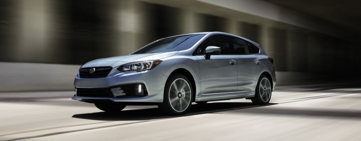 A silver 2020 Subaru Impreza for sale is shown driving through a tunnel.