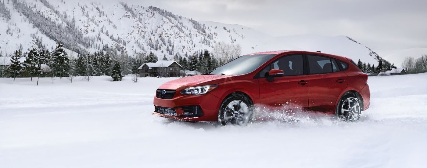 A red 2022 Subaru Impreza is shown driving through the snow.