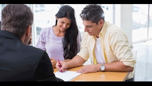 Couple signing auto loan paperwork at Maserati of Greensboro