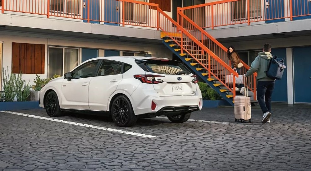 A white 2024 Subaru Impreza RS is shown parked a motel.