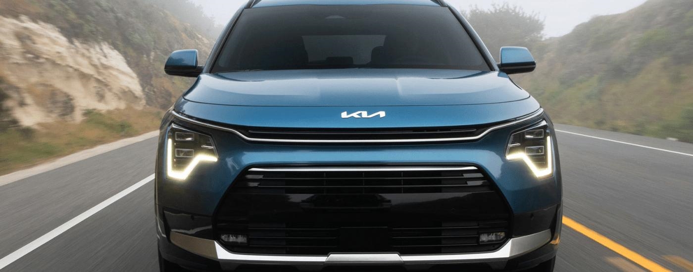 A blue 2023 Kia Niro Plug-In Hybrid is shown driving on a foggy road.