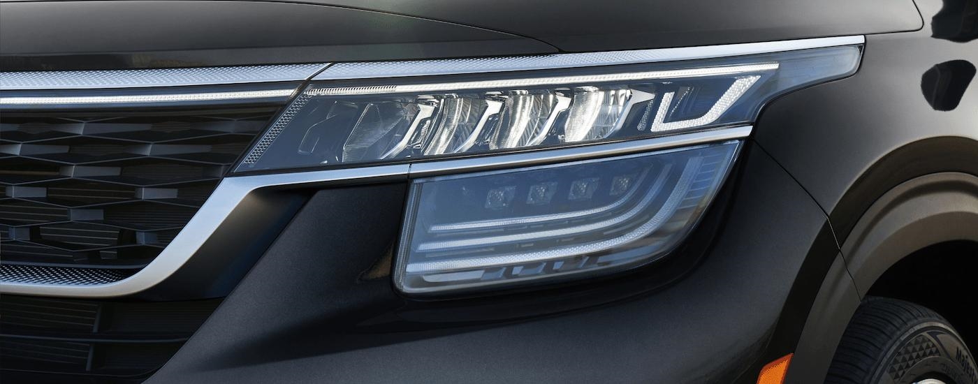 A close-up of the headlight on a black 2023 Kia Seltos is shown.