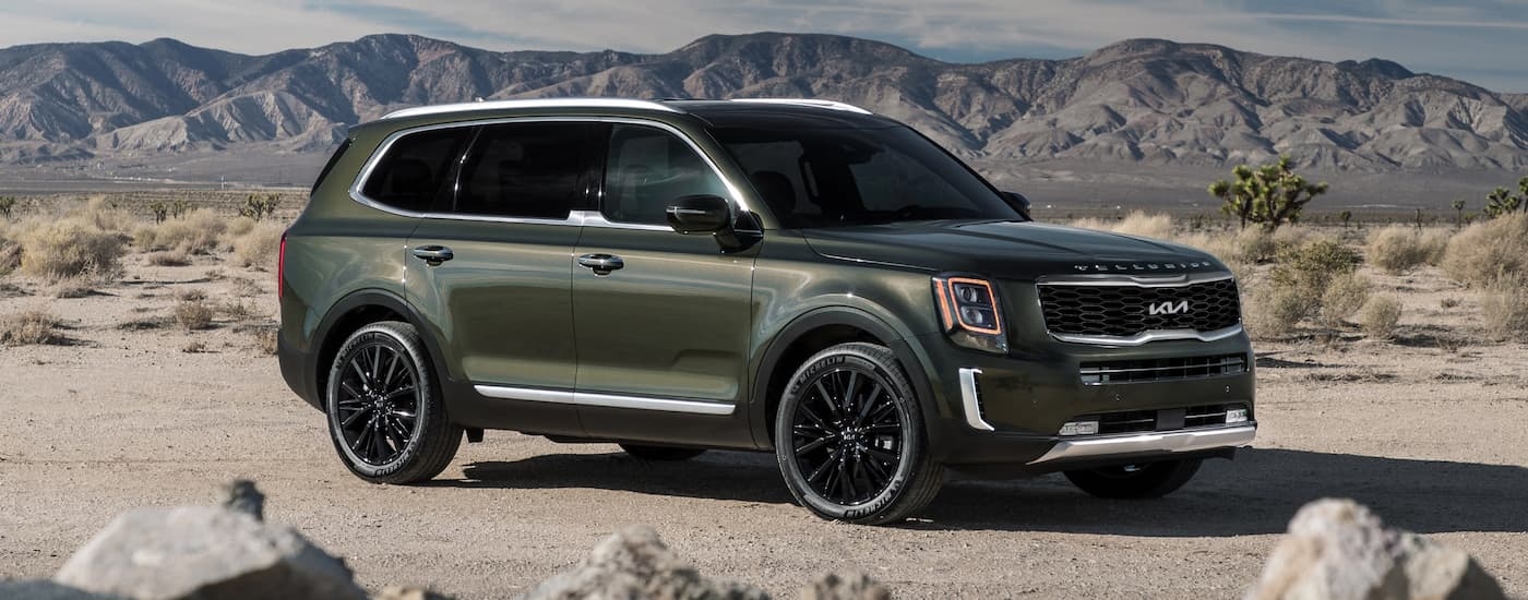 A green 2022 Kia Telluride is parked in front of mountains.