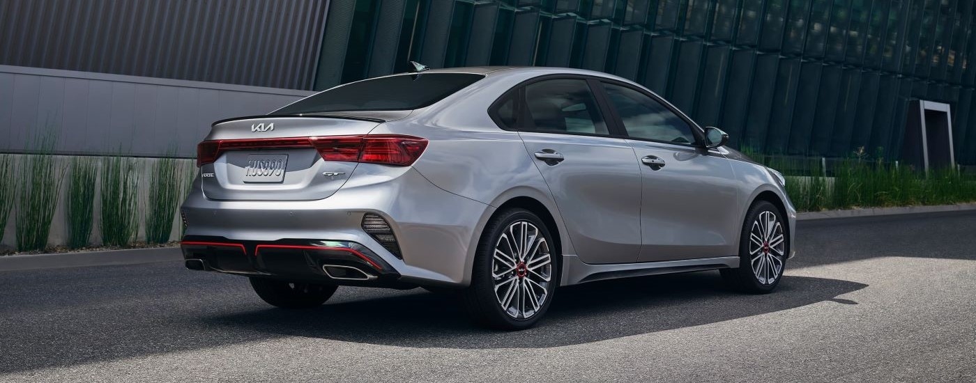 A silver 2022 Kia Forte GT is shown from a rear angle while parked in a city.