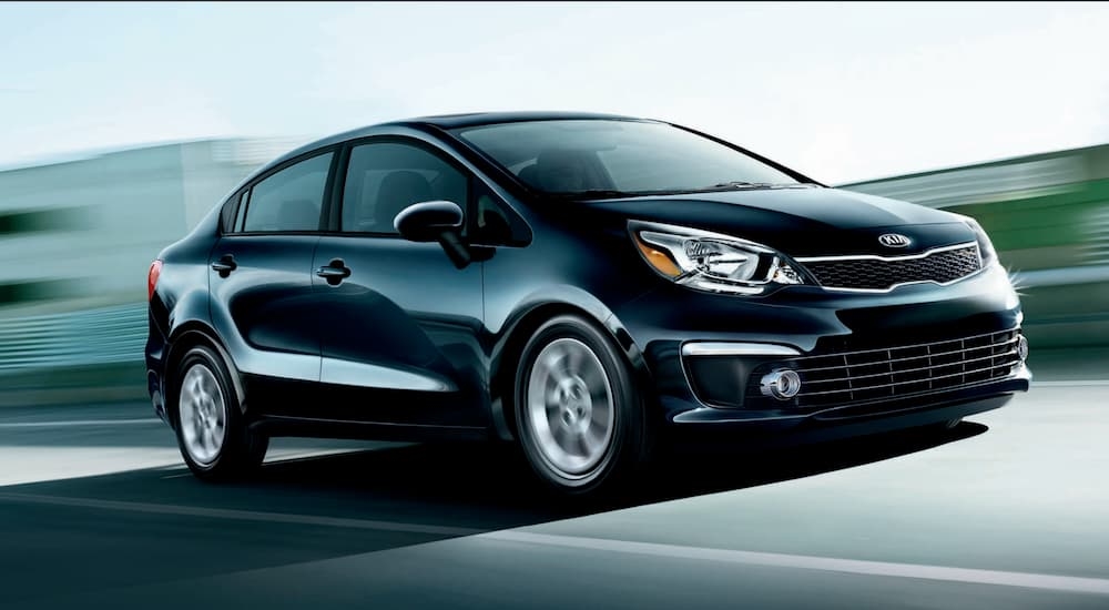 A black 2017 Kia Rio driving on the highway to a Kia dealer near you.