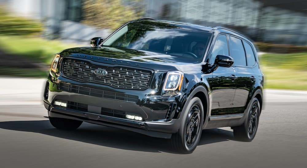 A black 2021 Kia Telluride driving on a city street after leaving a used Kia dealer near Port Lavaca.