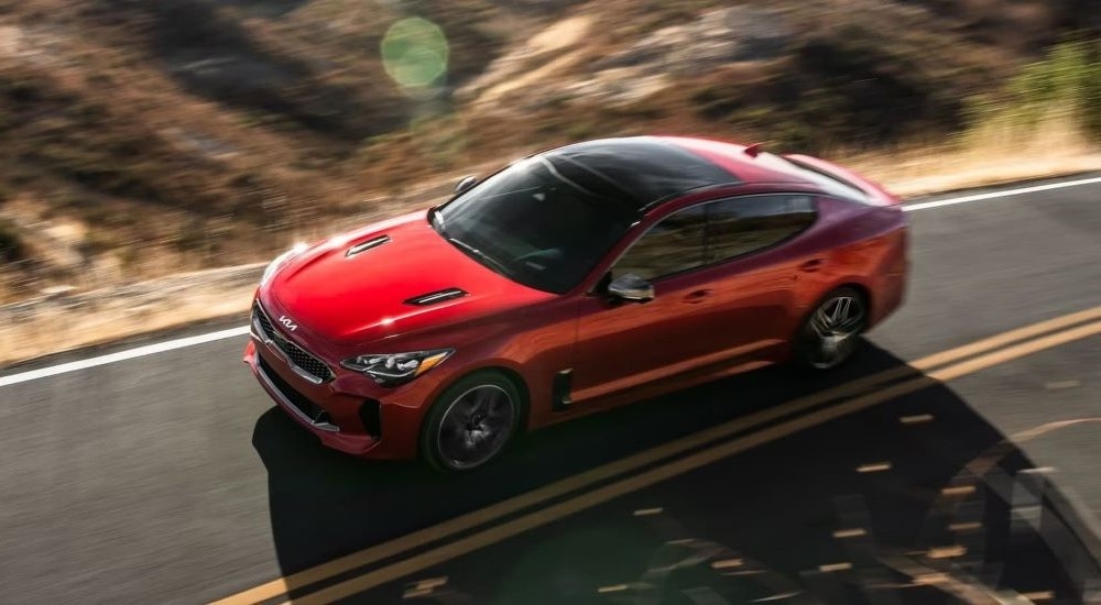 Aerial view of a red 2023 Kia Stinger driving on a sunny highway.